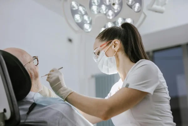 medic stomatolog și pacient pe scaunul dentistului, în semiprofil