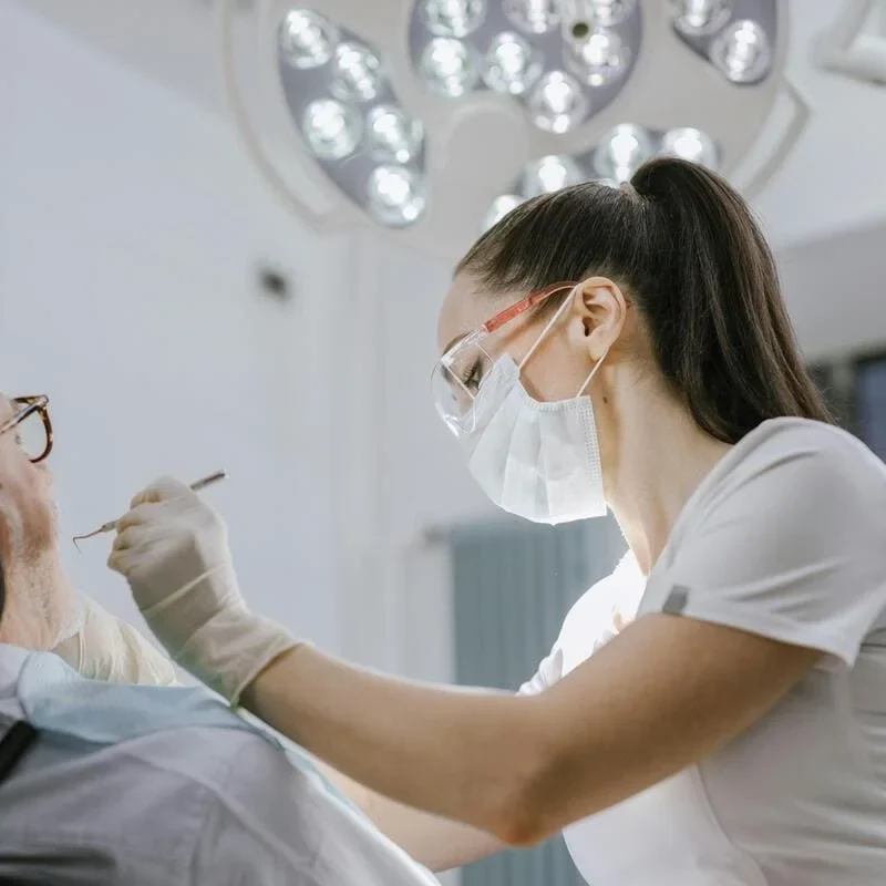 medic stomatolog și pacient pe scaunul dentistului, în semiprofil