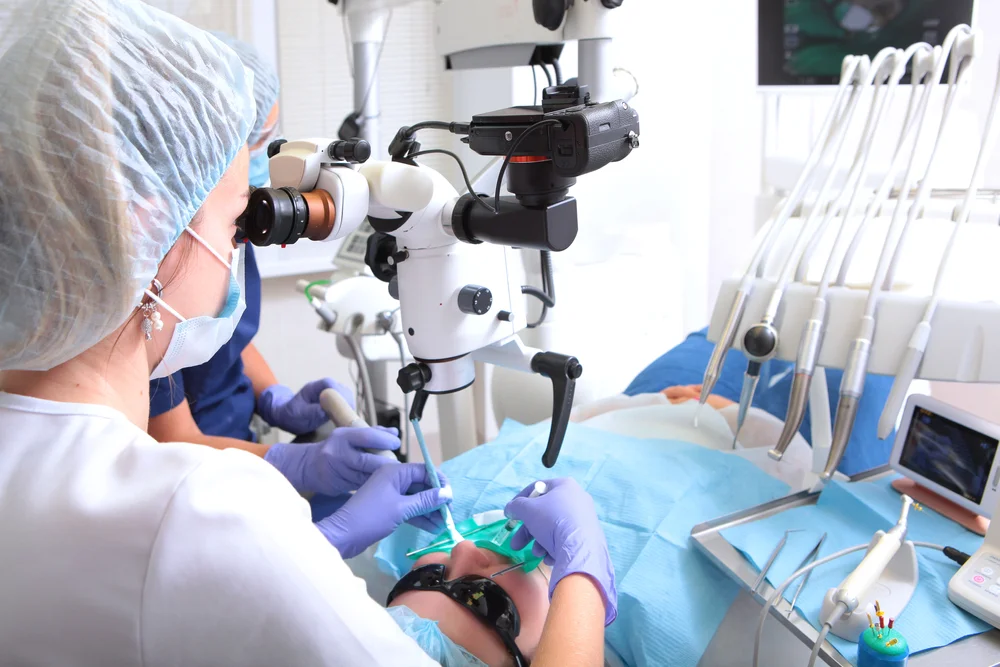 Stomatolog folosind microscop pentru tratamente dentare complexe